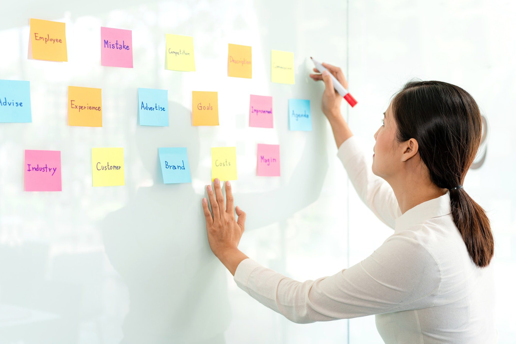 Businesswoman executive writing and taking notes keyword on board wall to planning about a business