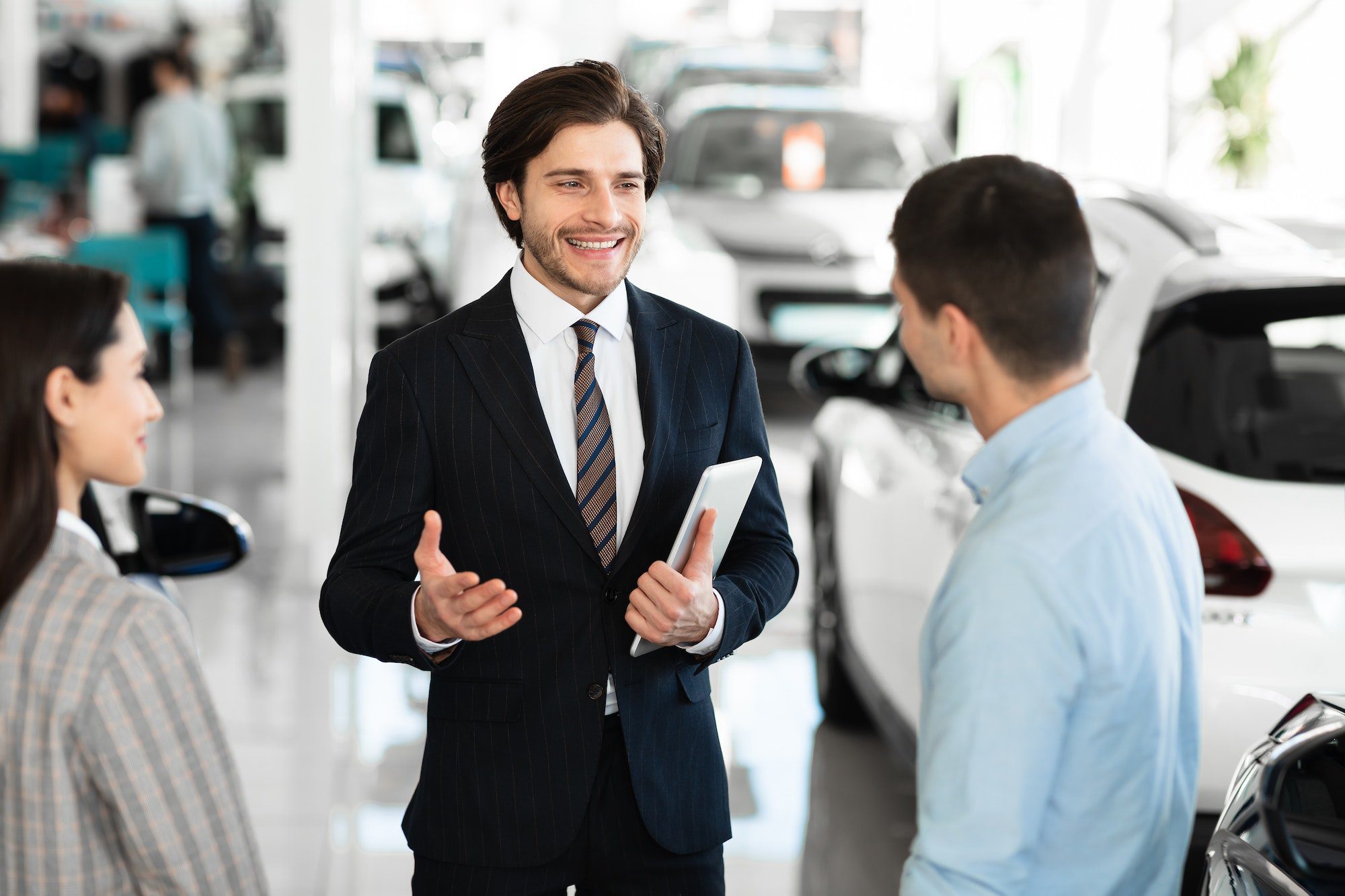Car dealer talking with clients selling them automobile