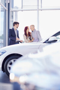 Car dealer with couple in showroom